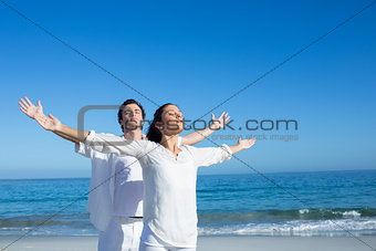Happy couple doing yoga beside the water