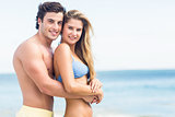 Happy couple in swimsuit looking at camera and embracing