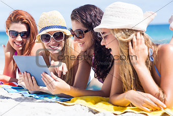 Happy friends wearing sun glasses and using tablet