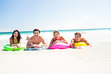 Happy friends lying on inflatable mattress above the water