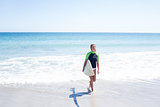 Fit blonde woman walking in the water and holding surfboard