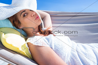 Pretty brunette posing with straw hat in the hammock