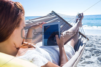 Brunette using tablet while relaxing in the hammock