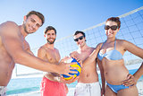 Group of friends holding volleyball and smiling at camera