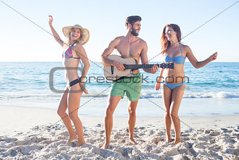 Handsome man playing guitar and his friends dancing