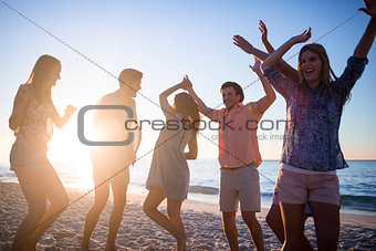 Happy friends dancing on the sand