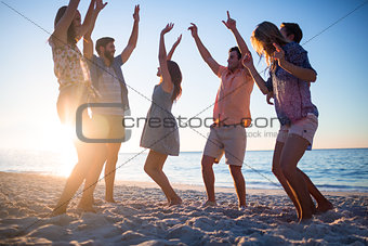 Happy friends dancing on the sand