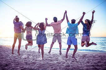 Happy friends holding hands and jumping