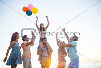 Happy friends dancing on the sand with balloon