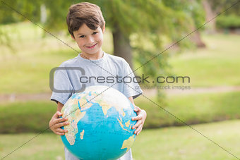 Smiling boy holding an earth globe in the park