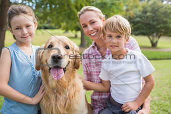 Happy family looking at camera and playing with their dog