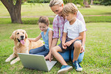 Happy family with their dog using laptop