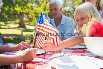 Happy family having picnic and holding american flag