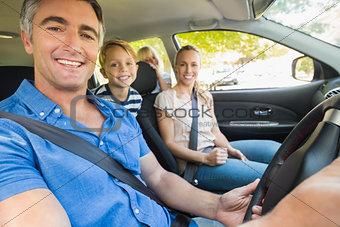 Happy family smiling at the camera in the car