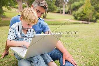 Happy father with his son using laptop in the park