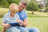 Happy father with his son using tablet in the park