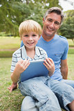 Happy father with his son using tablet in the park