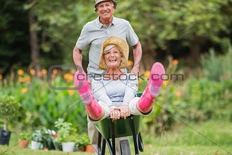 Happy senior couple playing with a wheelbarrow