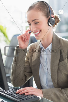 Smiling businesswoman with headset using computers