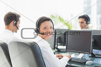 Businesswoman looking at camera while her colleagues working