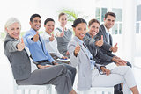 Business people looking at camera with thumbs up