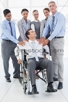 Businessman in wheelchair with his colleagues looking at camera
