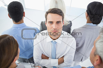Unhappy businessman looking at camera with his colleague around him