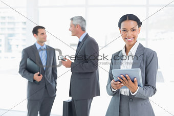Businesswoman using a tablet with colleagues behind in office
