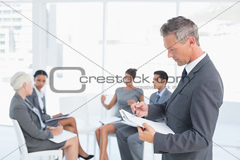 Businessman writing notes with colleagues behind