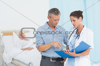 Doctor explaining report to female patient and husband