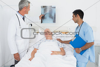 Male doctors examining x-ray with patient