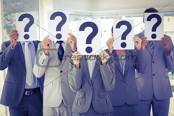 Business team holding question marks over face