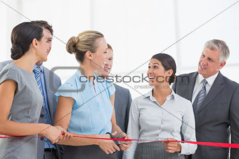 Happy business team cutting red ribbon