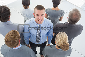 Businessman looking at camera and business team standing back to camera
