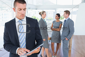 Businessman using tablet with colleagues behind him