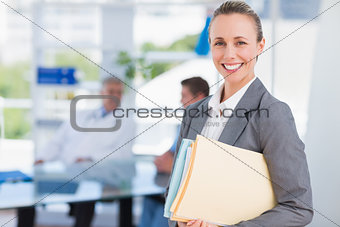 Smiling businesswoman holding files and looking at camera