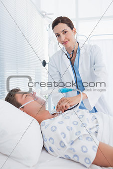 Smiling doctor auscultating her patients chest