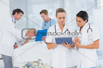 Doctors looking at clipboard while theirs colleagues speaks with patient