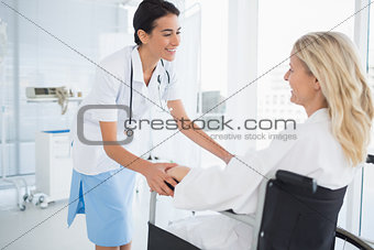 Happy doctor smiling at her patient in wheelchair