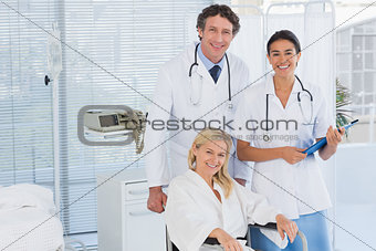 Doctors and patient in wheelchair smiling at camera