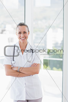 Happy doctor smiling at camera with arms crossed