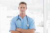 Confident male doctor looking at camera with arms crossed