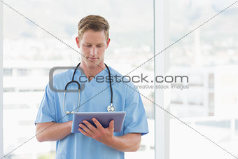 Doctor writing on clipboard beside windows