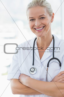 Happy doctor looking at camera with arms crossed