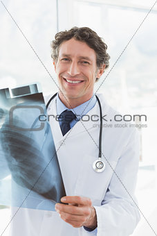 Happy doctor holding X-ray and smiling at camera