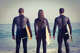 Friends on wetsuits with a surfboard on a sunny day