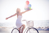 Beautiful blonde on bike ride holding balloons