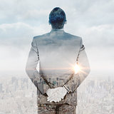 Composite image of young businessman standing with hands behind back