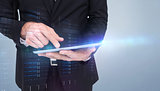 Composite image of mid section of a businessman touching digital tablet