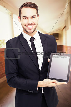 Composite image of smiling businessman showing his tablet pc